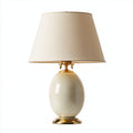 Lampada da tavolo in ceramica bianca con base decorativa in oro e paralume in tessuto beige